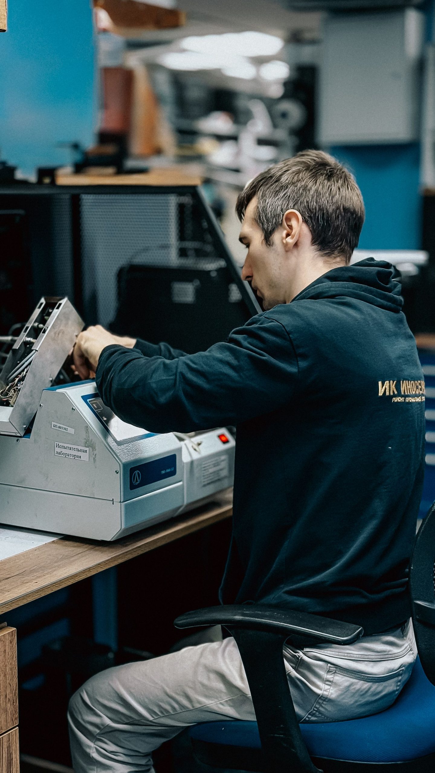 A man working at a printer machine in an office setting, focusing on technical tasks.